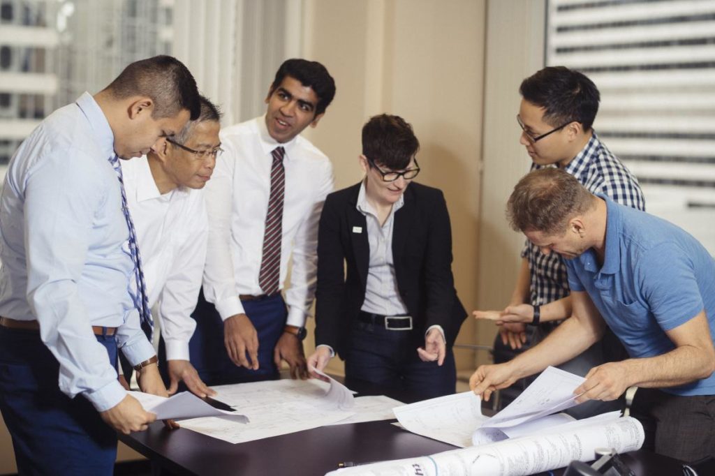 Large group of Singh employees looking at plans together